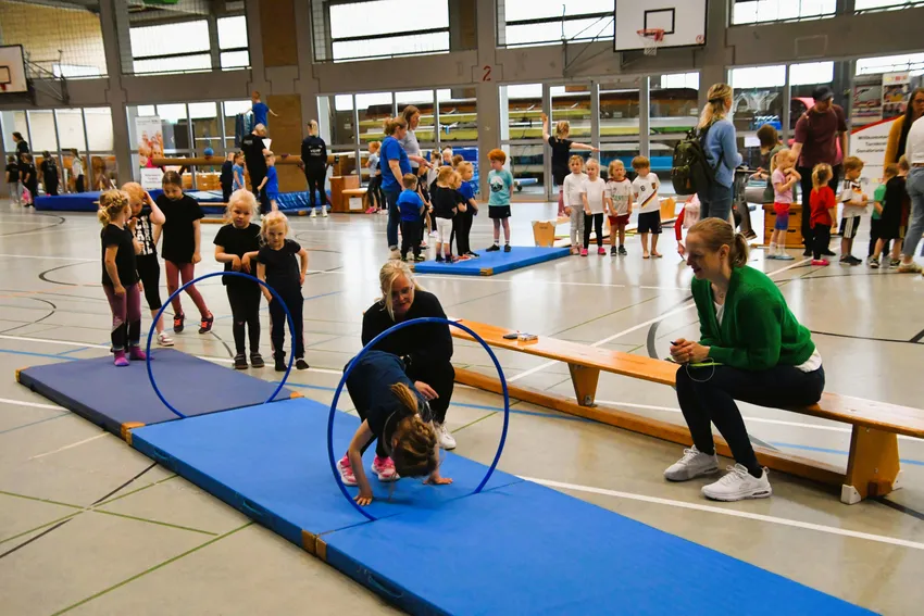 2 Rollen vorwärts durch den aufgestellten Reifen in den sicheren Stand, aufstehen, ohne nachfassen der Hände, nach der zweiten Rolle einen Strecksprung turnen. 