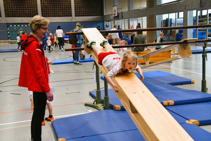 Eine Bank, die am unteren Holm eingehängt ist, hochsteigen, am oberen Holm festhaltend  seitwärts zu der am oberen Holm eingehängten Bank gelangen. Auf der Bank bäuchlings abwärts rutschen, unten eine Rolle vorwärts turnen.